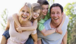 Couple giving two young children piggyback rides smiling