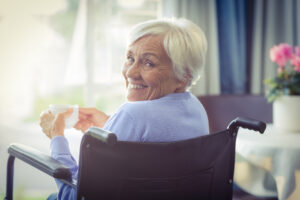 Happy senior woman on wheelchair holding a cup of tea