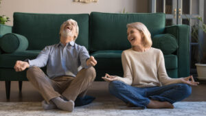 Laughing aged spouses sitting on floor in lotus position