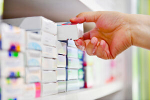 Closeup pharmacist hand holding medicine box in pharmacy drugsto